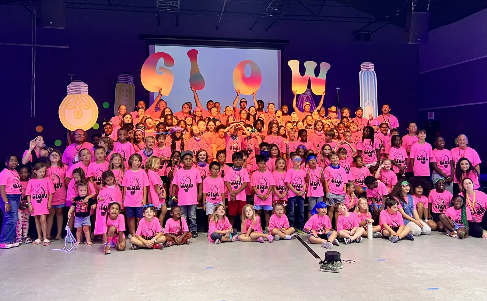 Campers and leaders in pink shirts filling the chapel for the camp photo