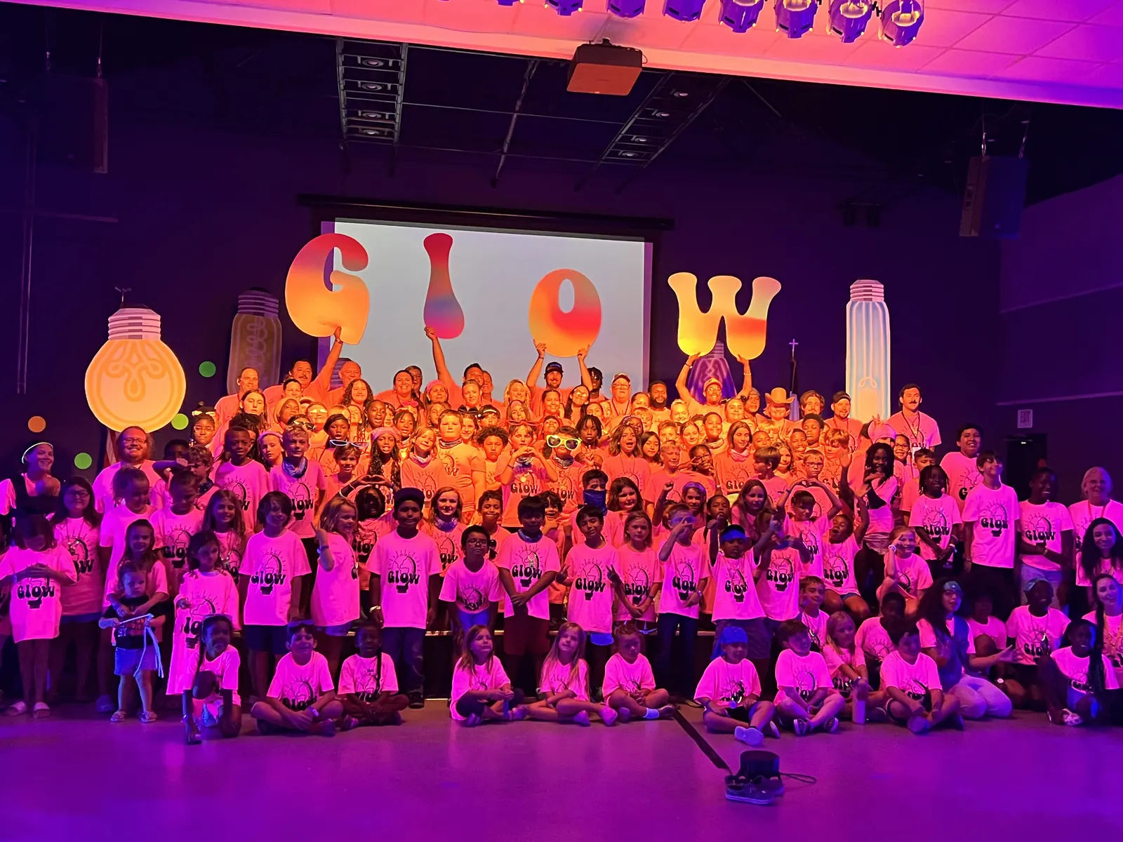 The camp group photo under glowing purple stage lights