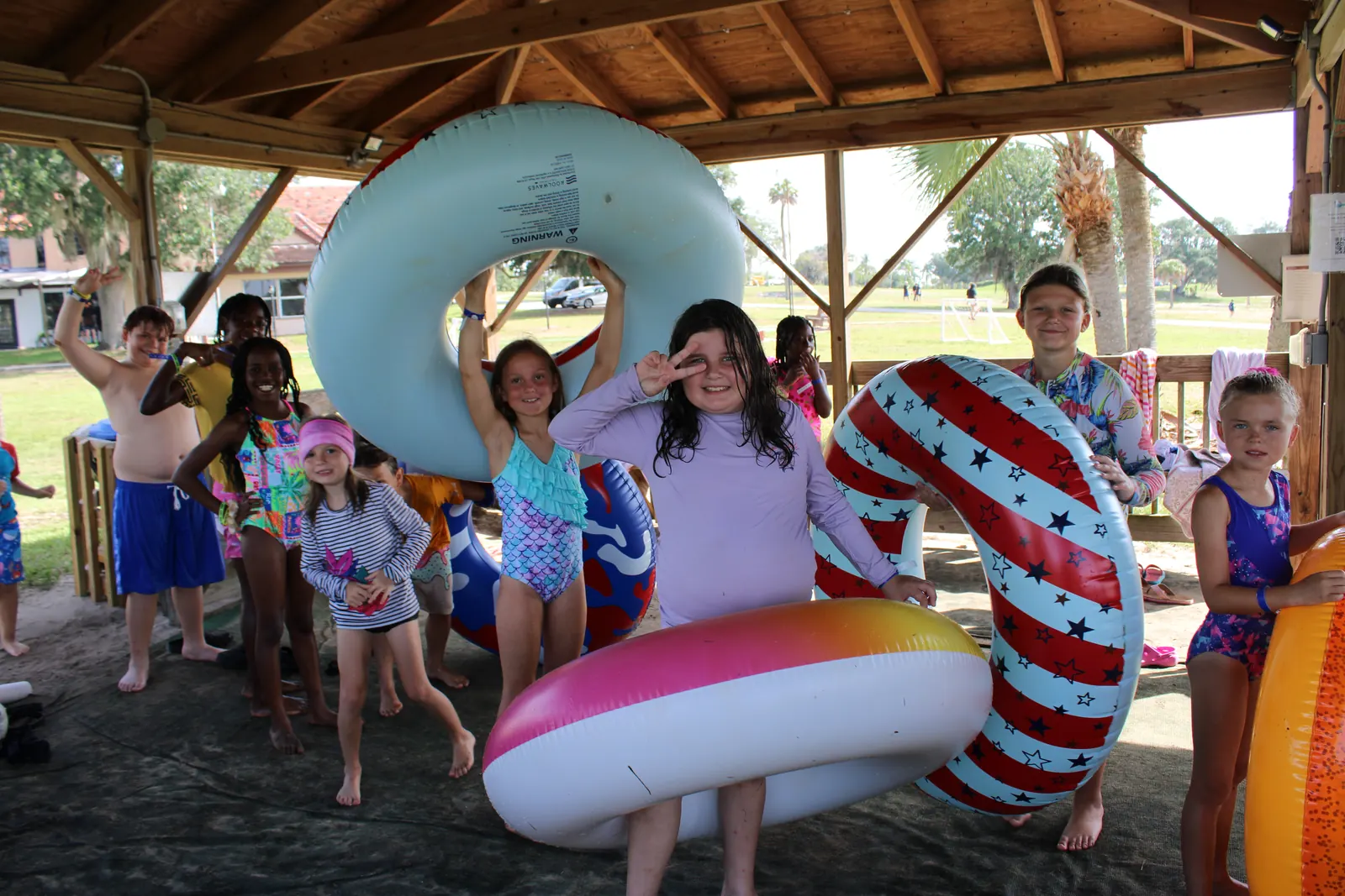 Campers with giant pool floats under the beach pavilion