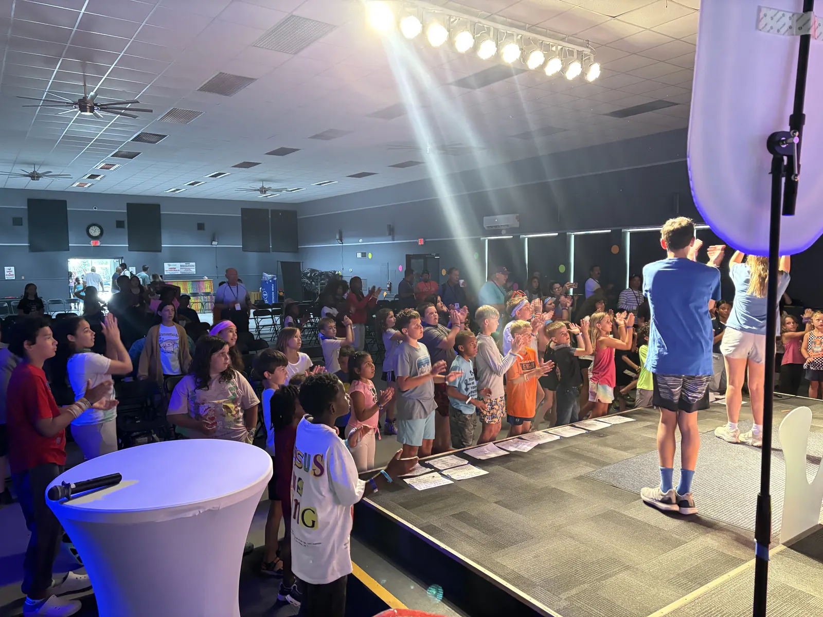 Campers worshiping under bright stage lights