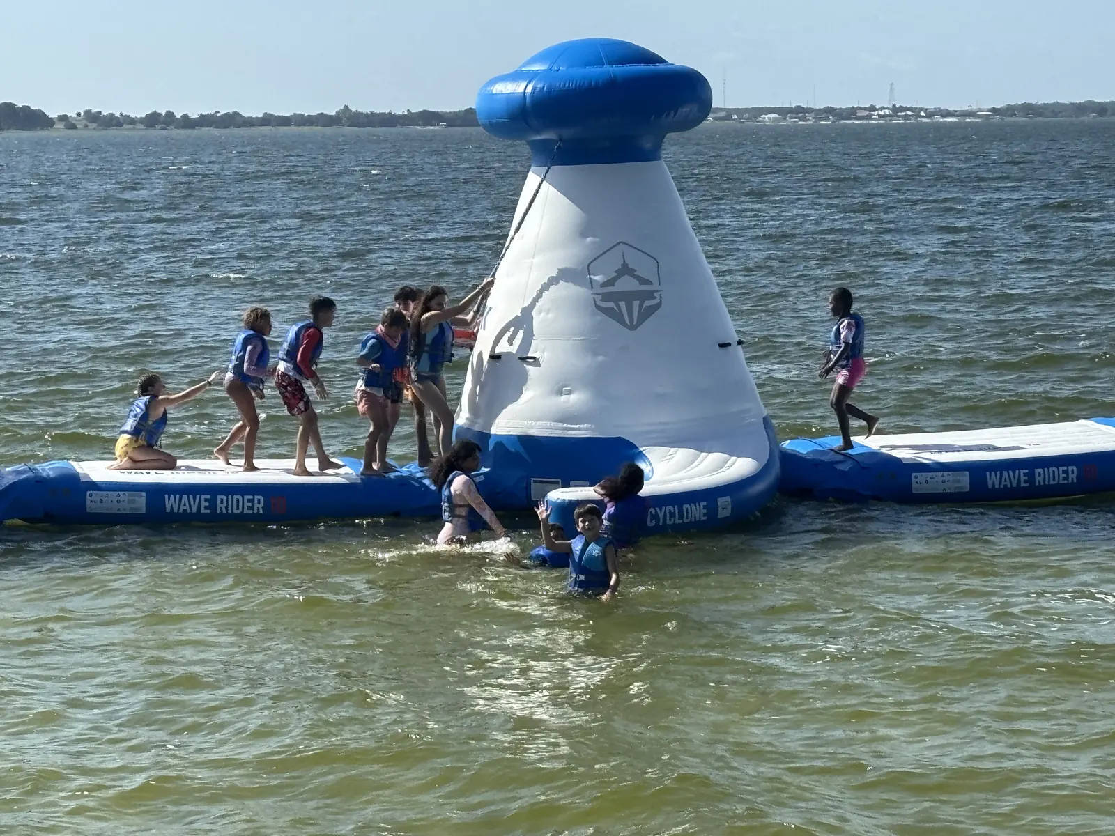 Campers climbing the inflatable on the lake