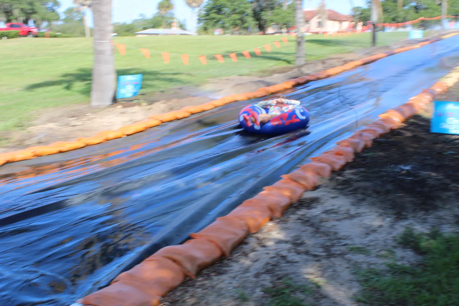 A camper riding the slip 'n slide on a tube