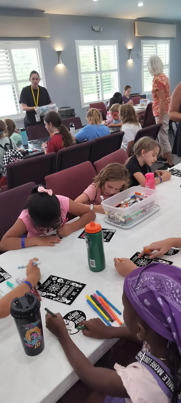 Campers working on crafts at long tables